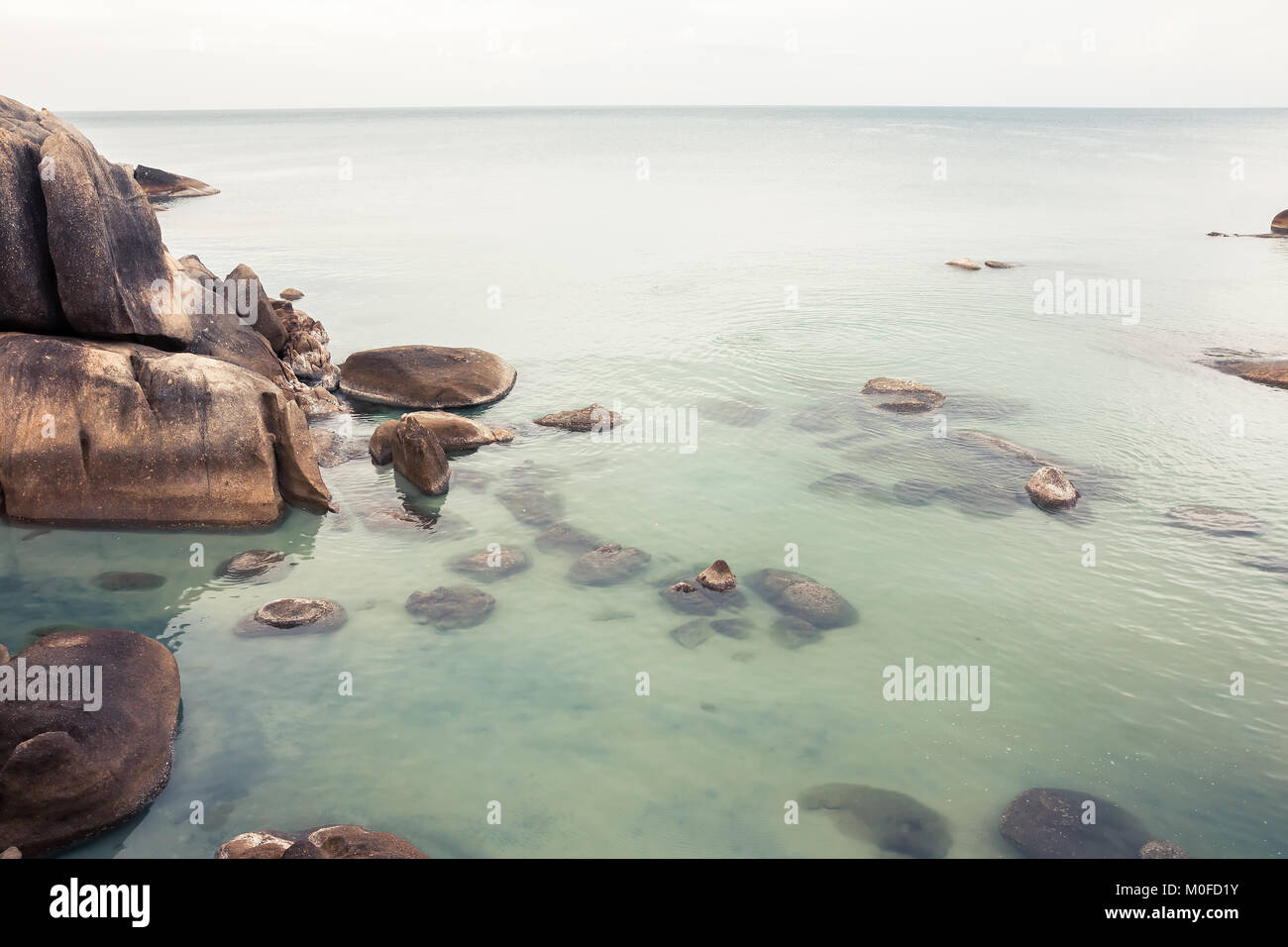 Tropical Beach Urlaub Landschaft mit ruhigen türkisfarbenen Meer und große runde Steine und Felsen im Meer Stockfoto