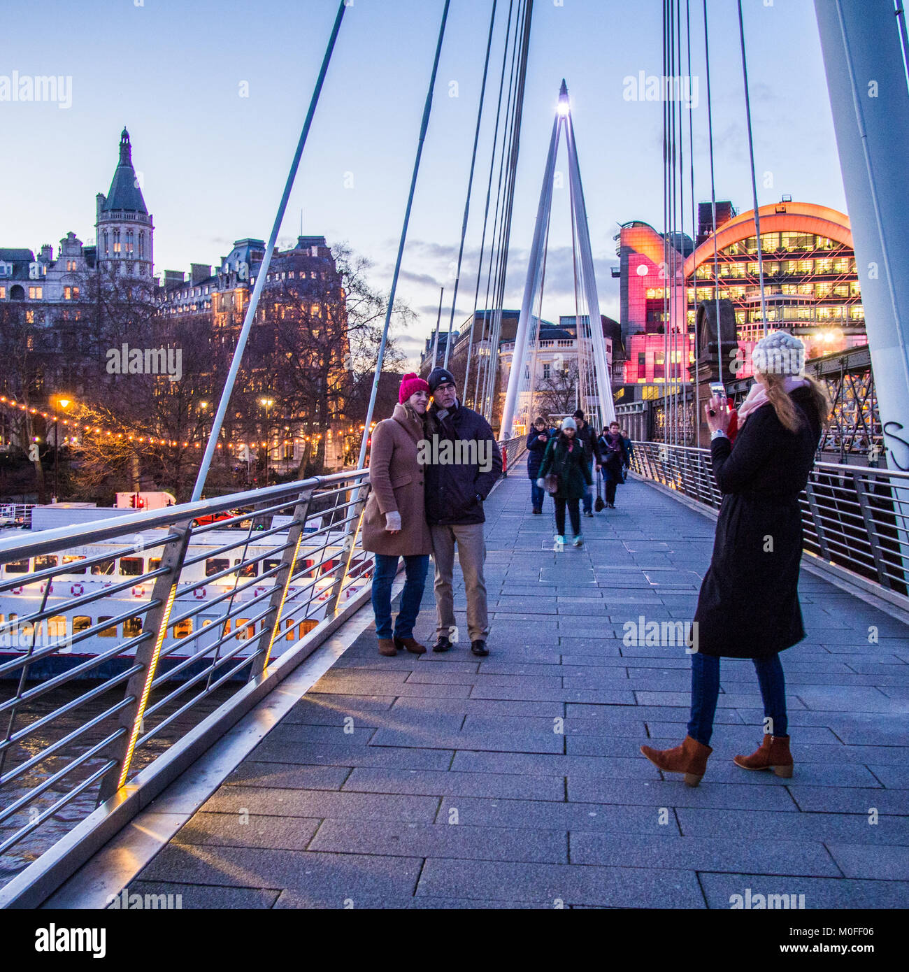 Leute für ein Foto auf Golden Jubilee Bridge London posieren. Hungerford Eisenbahn Brücke ist auf der rechten und die Charing Cross Station im Hintergrund. Stockfoto