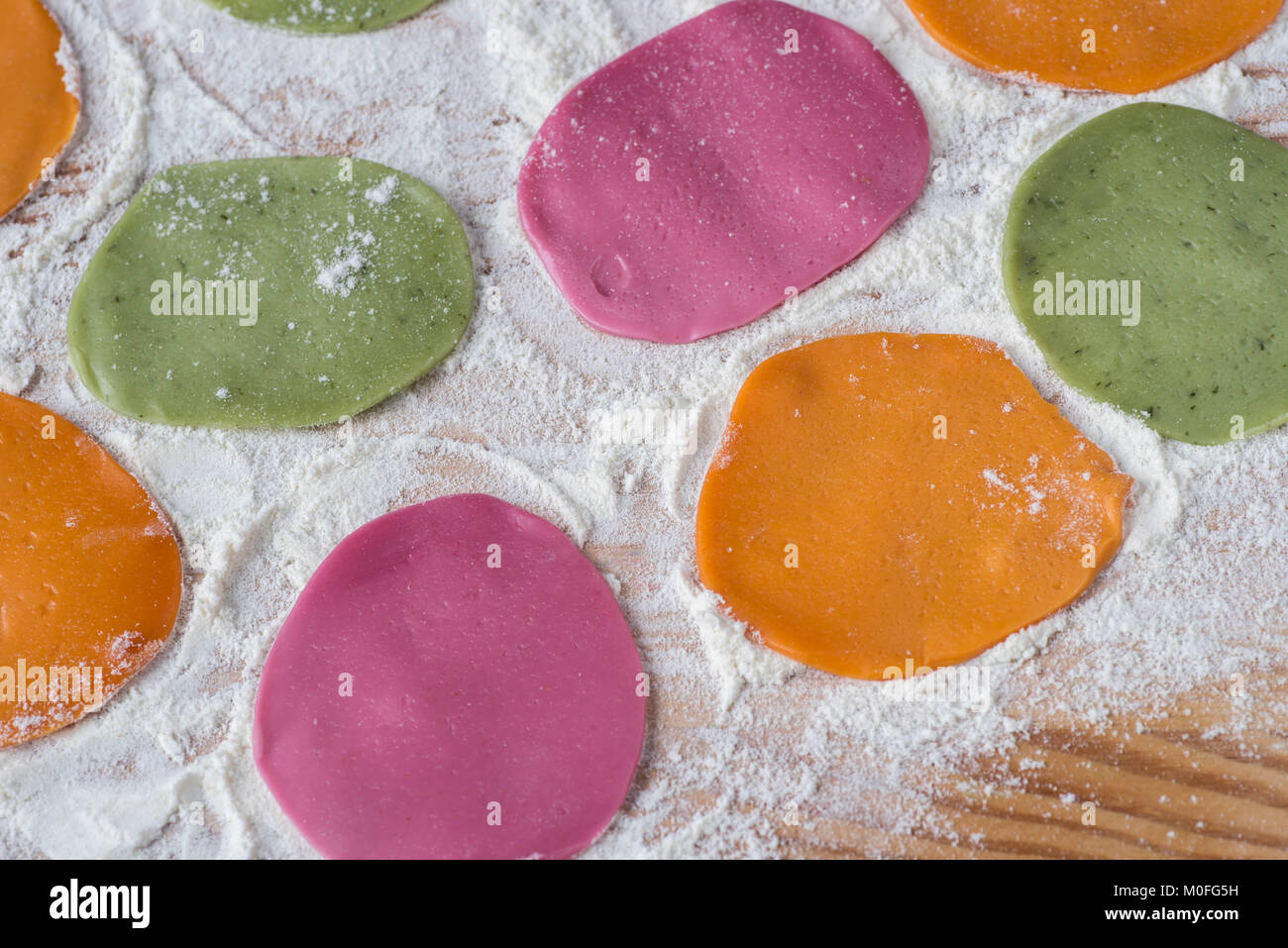 Bunt gefärbte Stücke von rohem Teig für Knödel auf Tisch Stockfoto