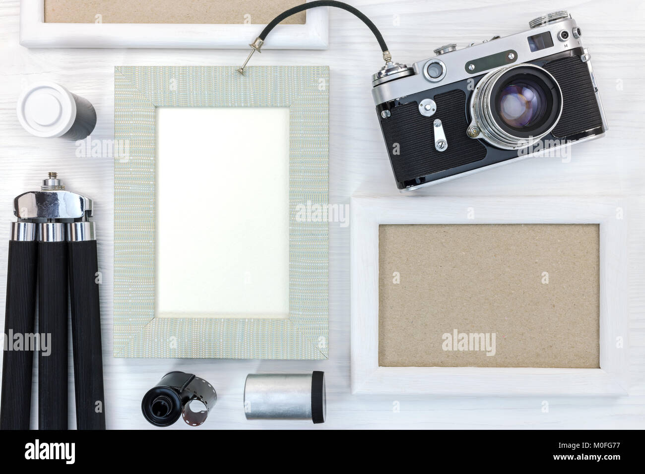 Alte Erinnerungen Konzept - retro Kamera, leeren Fotorahmen, Negativ Filme und Stativ auf weiße Holztisch Stockfoto