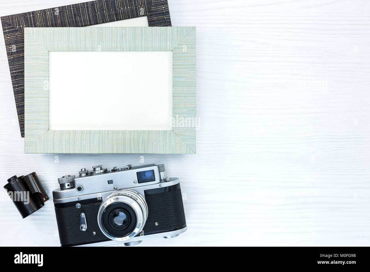 Retro Kamera mit Film Roll und zwei leeren Fotorahmen auf weißem Schreibtisch aus Holz Stockfoto