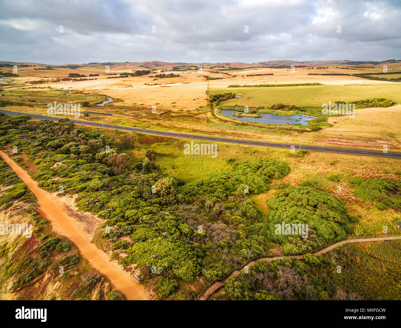 Ländliche Straße durch Wiesen und Weiden in Australien vorbei - Luftbild Landschaft Stockfoto