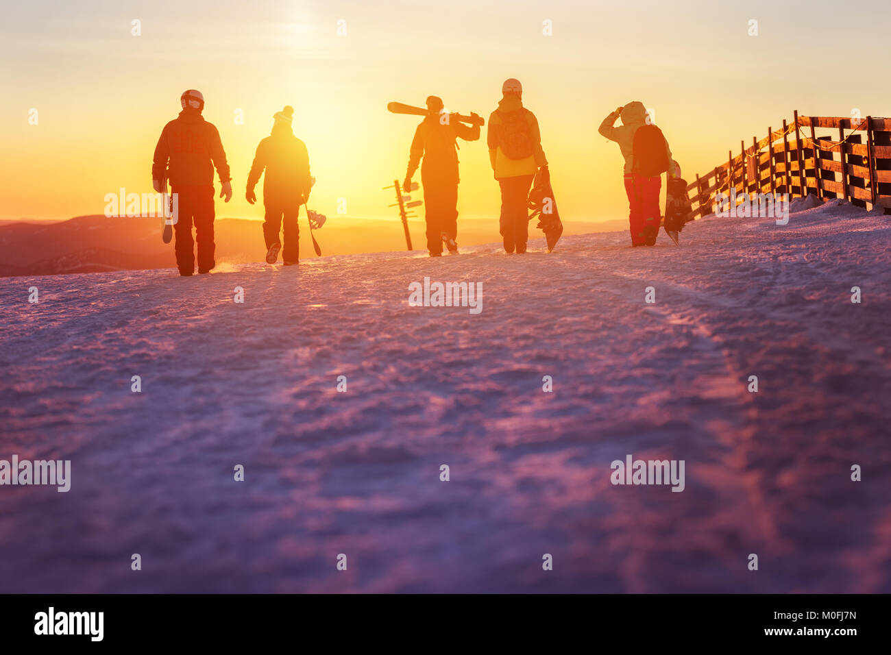 Freunde mit Ski und Snowboards zu Fuss bis Sonnenuntergang Stockfoto