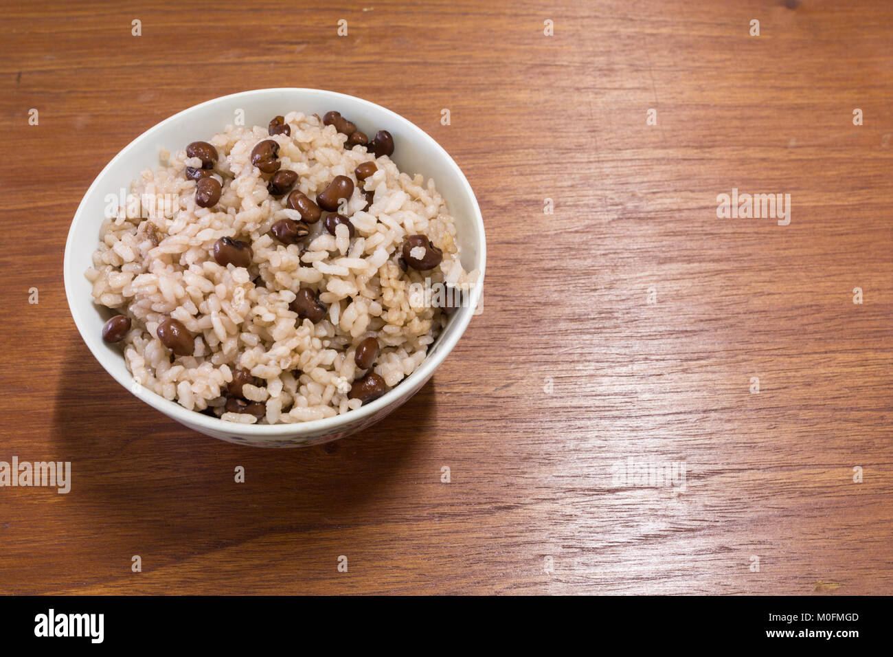 Gekochte rote Bohnen und Japanischen Reis in Weiß Schüssel, Mitte links, auf hölzernen Tisch Stockfoto