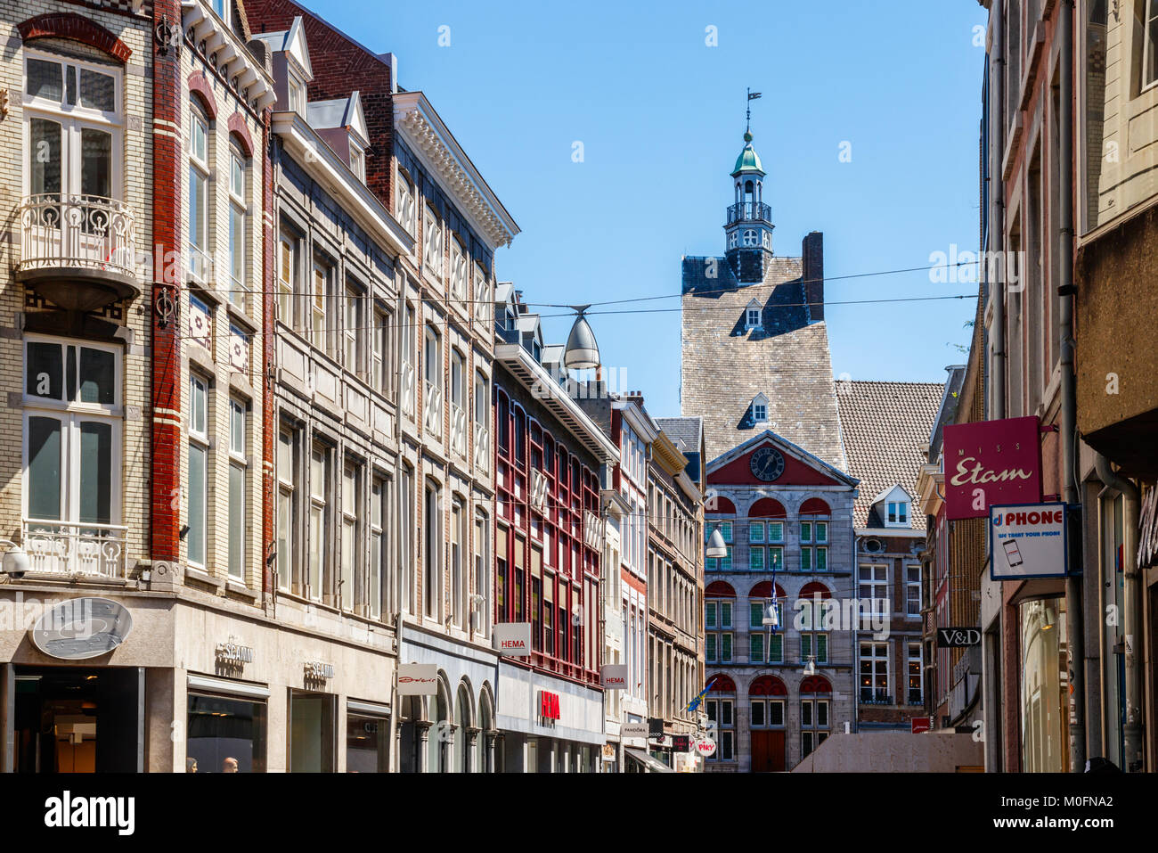 Grote Straat ("Big Street') mit dem 'inghuis' und die Fassaden der Häuser und Geschäfte unter einem blauen Himmel an einem sonnigen Tag, Maastricht, Niederlande. Stockfoto