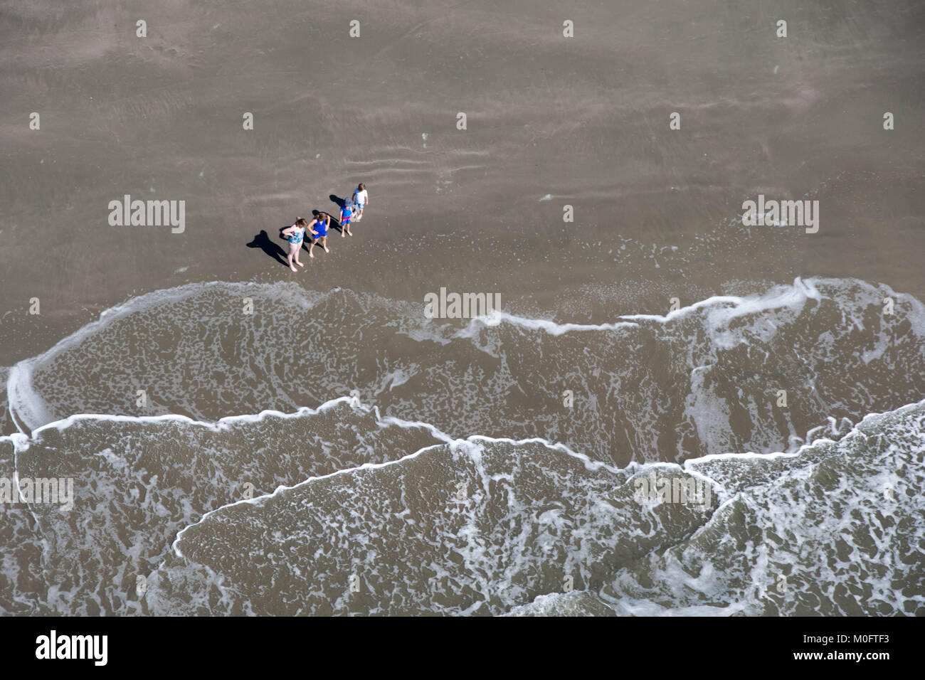 Familie steht am Rande von Tide am Beach, South Carolina Stockfoto
