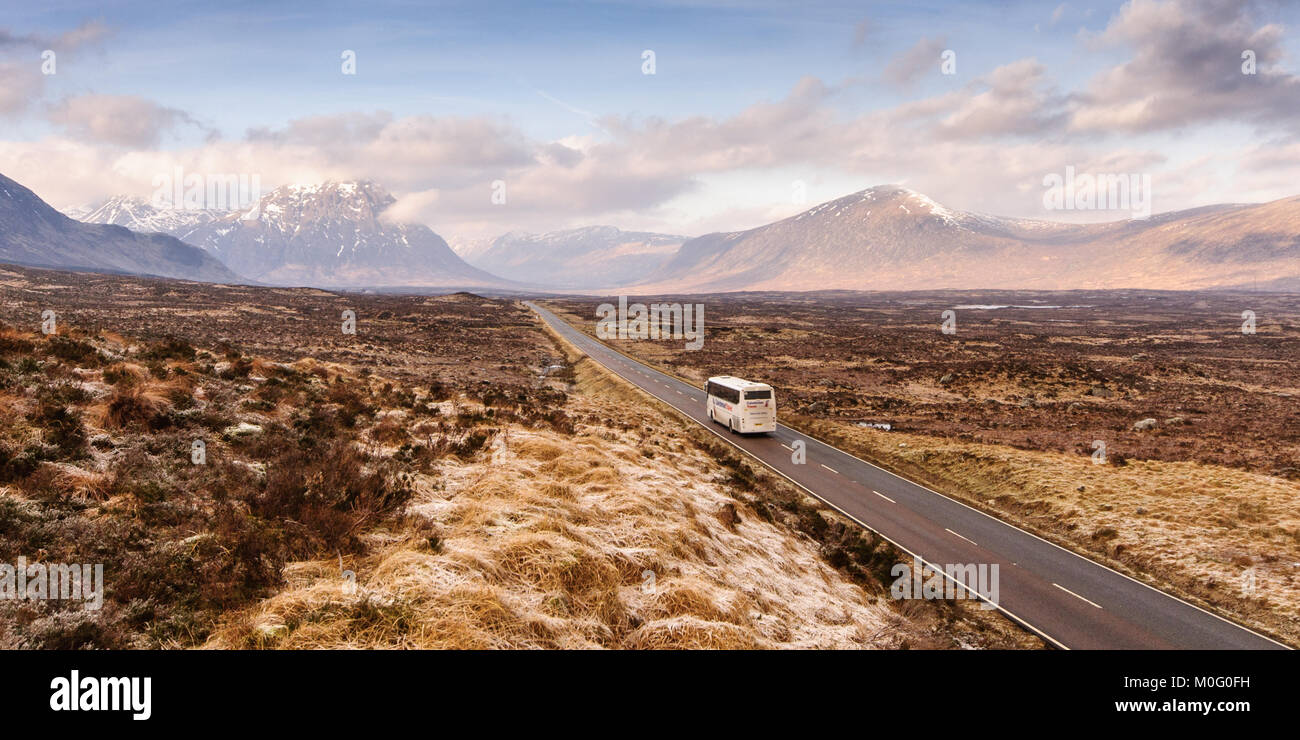 Glen Coe, Schottland, Großbritannien - 16 Januar, 2012: ein Tourist Bus entlang der A82 Hauptstraße, in der weiten und trostlosen Winterlandschaft von Rannoch Moor Torf Stockfoto