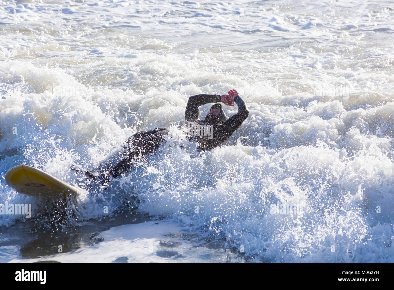 Surfer Herabfallen von Surfbrett, das Beste aus den großen Wellen und abgehackt Meere in Bournemouth, Dorset UK im Januar Stockfoto