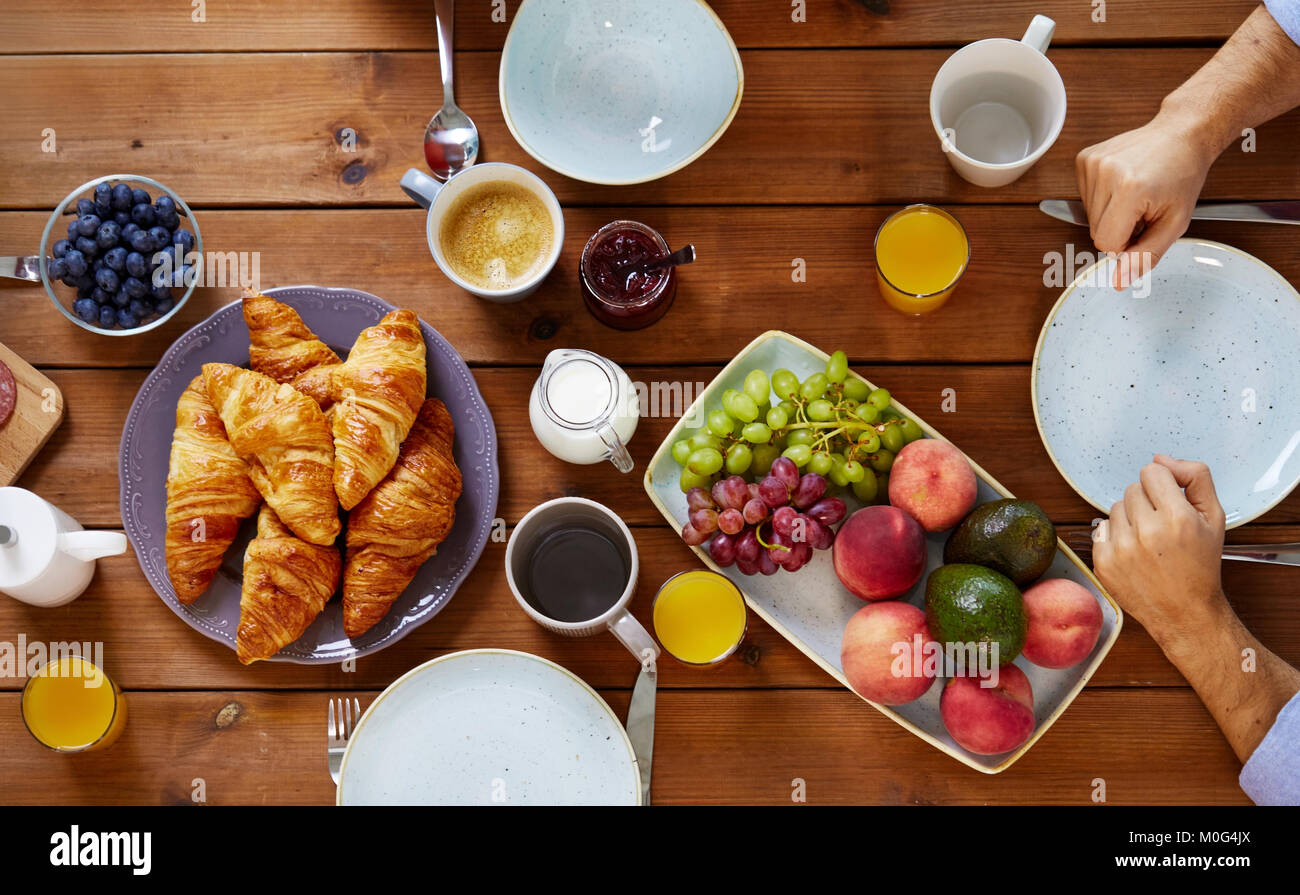 Die Hände des Menschen dem Frühstück am Tisch mit dem Essen Stockfoto