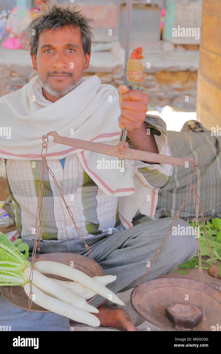 BUNDI, Rajasthan, Indien - Dezember 08, 2017: Portrait eines Verkäufers Holding eine herkömmliche Waage am Gemüsemarkt Stockfoto