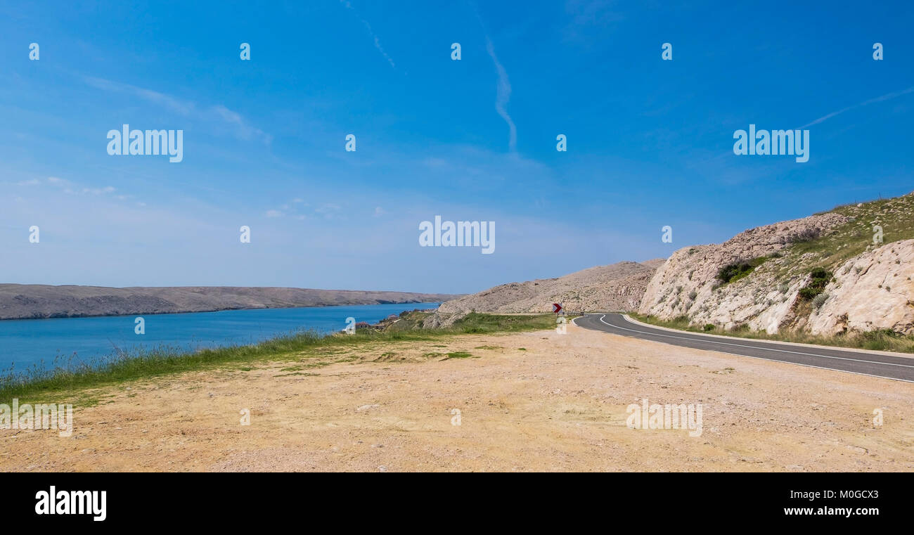 Eine kurvenreiche Straße entlang dem Meer auf der felsigen Insel Pag, Kroatien. Stockfoto