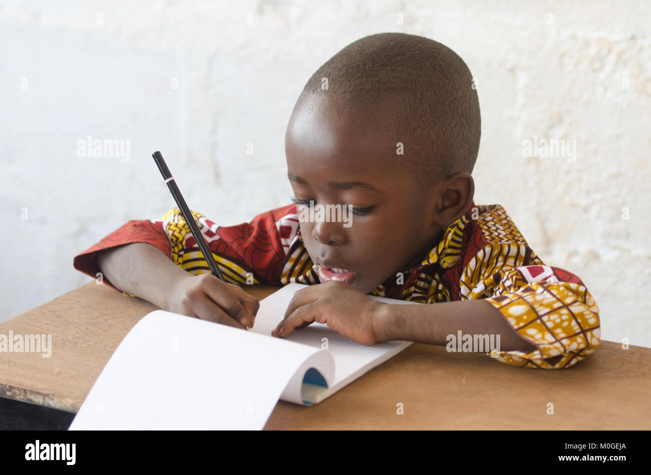 Gutaussehenden jungen afrikanischen Jungen Schreiben und Lernen in der Schule Gebäude Stockfoto