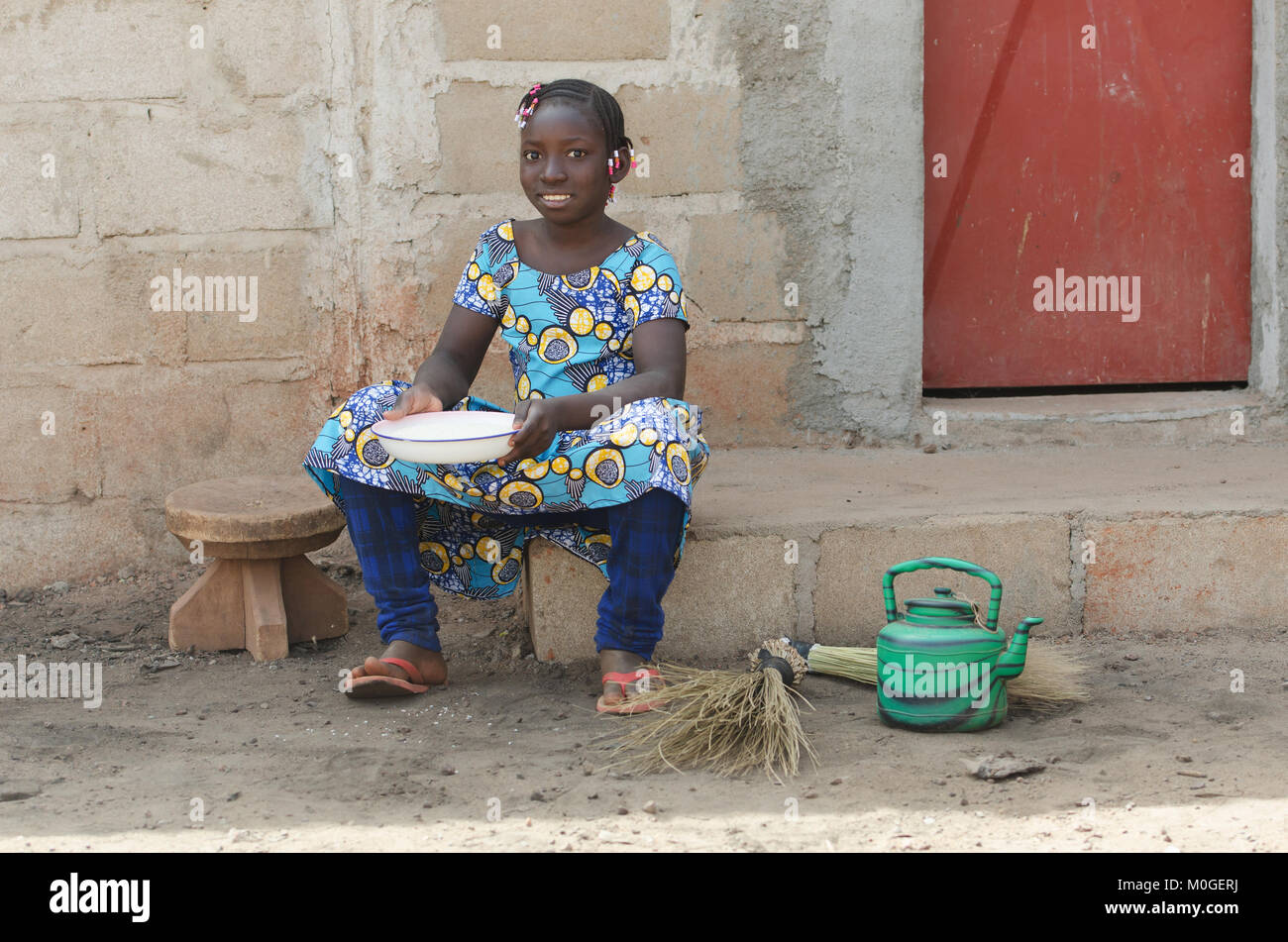 Kleines afrikanisches Mädchen Reis Kochen im Freien lächelnd an Kamera Stockfoto