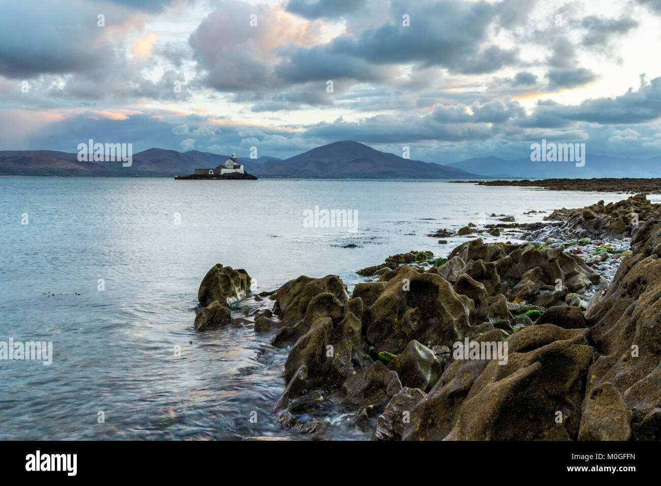 Fenit Leuchtturm aus einem felsigen Ufer am Abend. Stockfoto