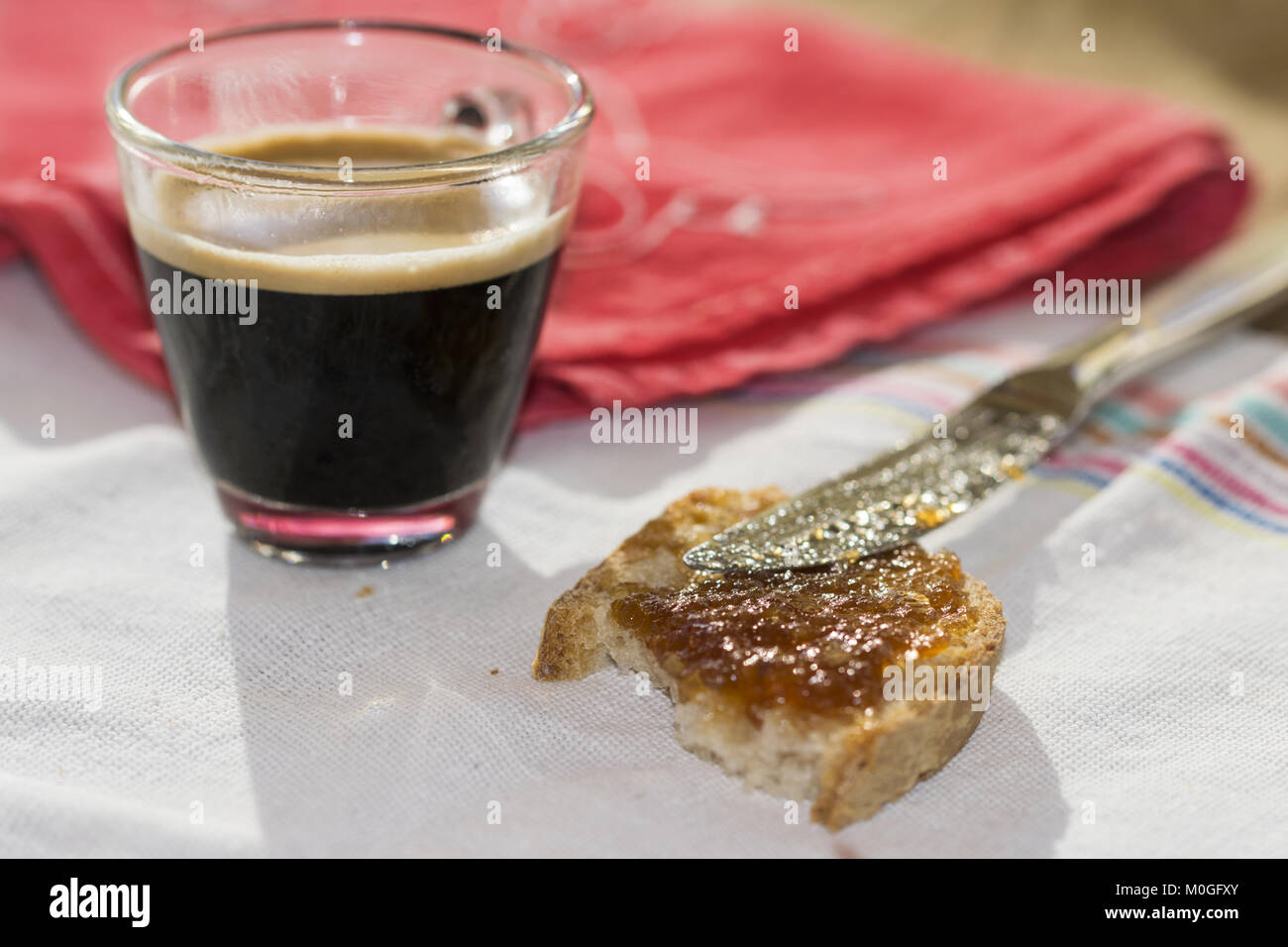 Tasse Espresso Kaffee mit Scheibe Brot und Erdbeermarmelade Stockfoto