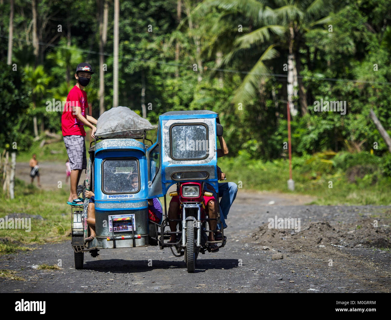 Camalig, Albay, Philippinen. 22 Jan, 2018. Die Menschen fahren mit dem Philippinischen Dreirad Taxi, während sie ihre Gemeinschaften an den Hängen des Mayon Vulkan verlassen. Es gab eine Reihe von Eruptionen auf der Mayon Vulkan in der Nähe von Legazpi Montag. Die Eruptionen begann Sonntag Nacht und weiter durch den Tag. Um ca. 12.00 Uhr den Vulkan gesendet eine Wolke aus Asche und Rauch hoch über Camalig, die größte Gemeinde in der Nähe des Vulkans. Credit: ZUMA Press, Inc./Alamy leben Nachrichten Stockfoto