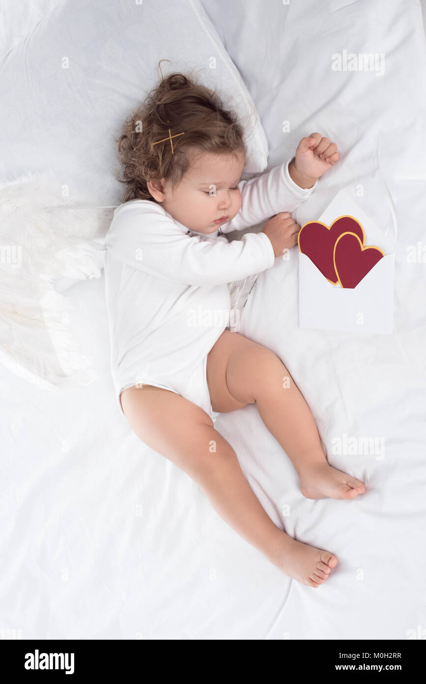 Wenig Putto mit Flügeln liegend auf Bett mit Herz Stockfoto