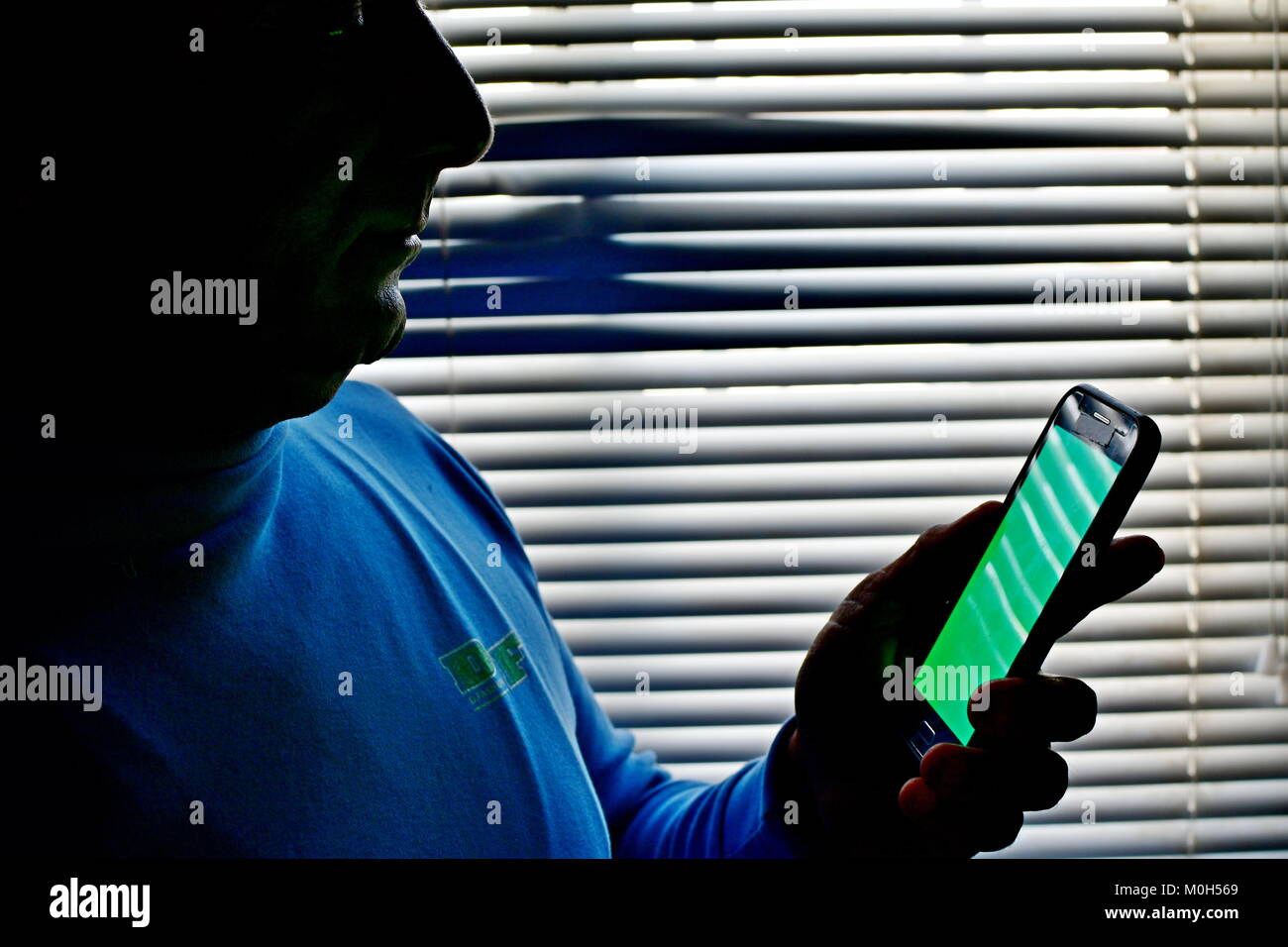 Grüner Bildschirm Bereit Android und mann Betrachtung gegen gestreifte Fenster von Schatten und Licht Muster Stockfoto