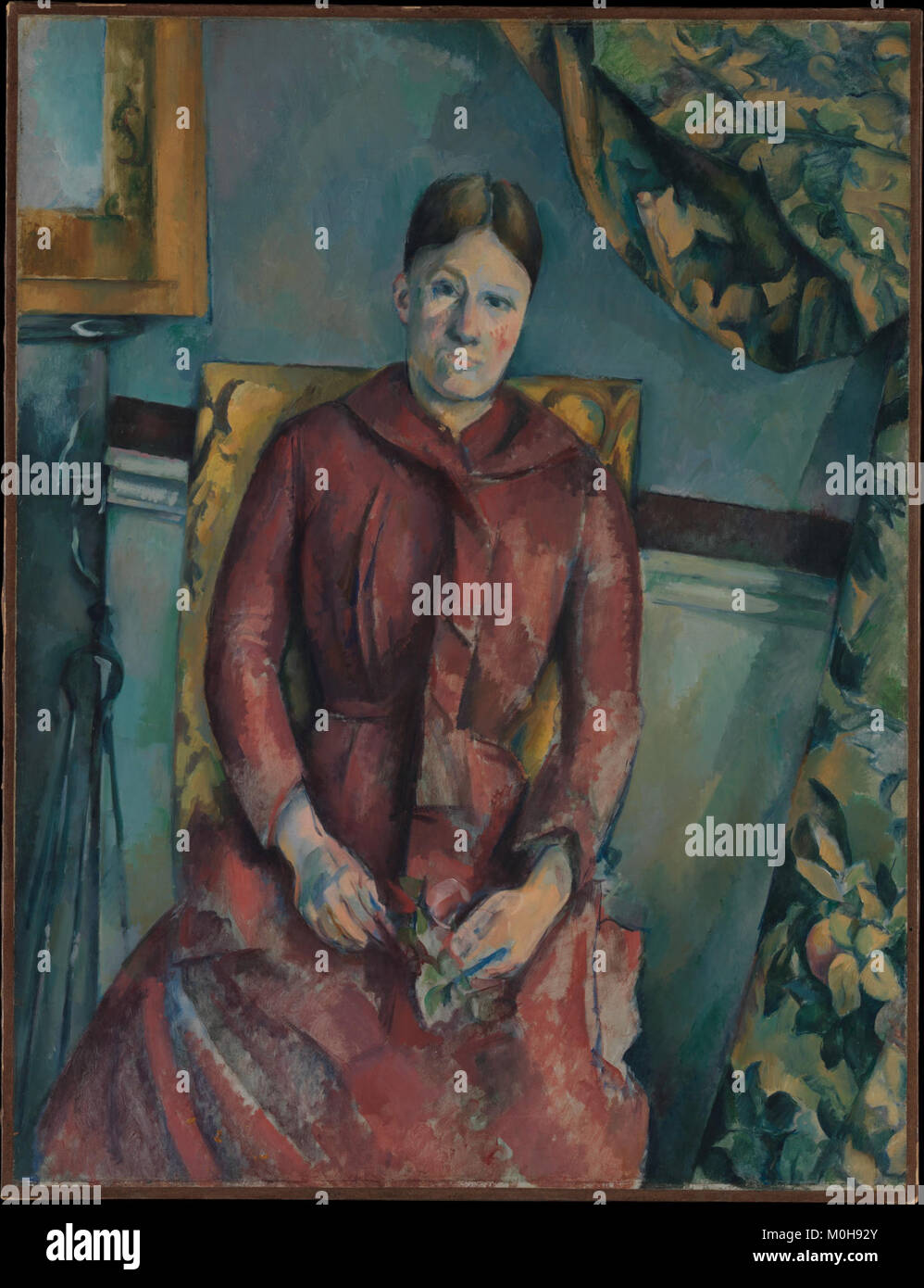 Dieses Porträt von Paul Cézanne zeigt Hortense Fiquet, die Frau des Künstlers, in einem roten Kleid. Das Gemälde, das Ende des 19. Jahrhunderts geschaffen wurde, zeigt Cézannes charakteristische Pinselarbeiten und Farbgebrauch, um sein Motiv mit subtiler emotionaler Tiefe darzustellen. Stockfoto