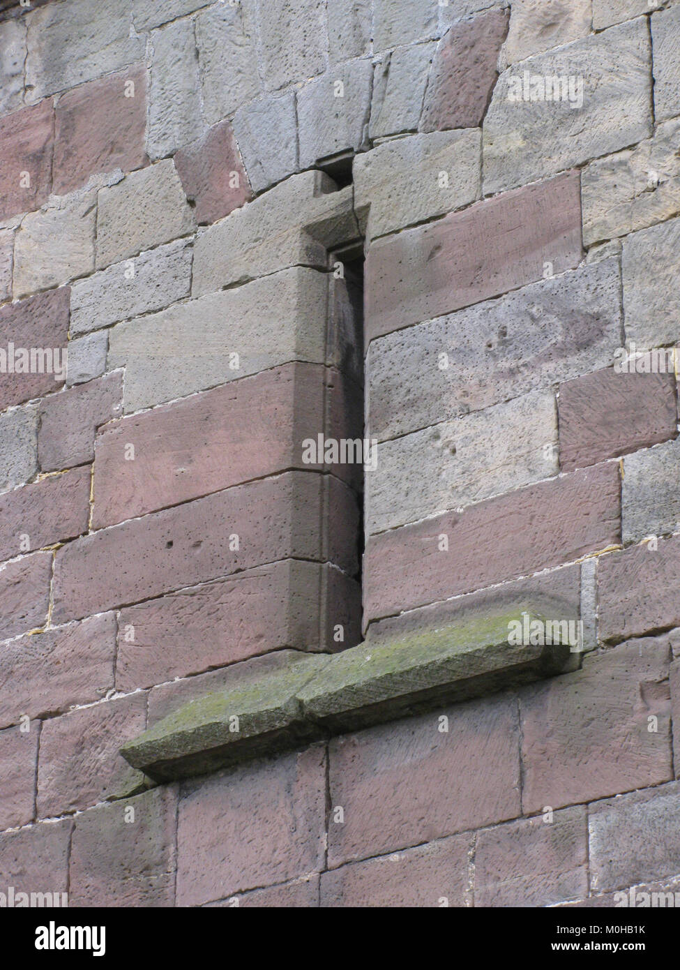 Die Burg Adelebsen in Deutschland verfügt über einen mittelalterlichen Pfeilschlitz oder ein Schießloch zur Verteidigung, das Elemente der Festungsarchitektur und des historischen Militärbaus darstellt. Stockfoto