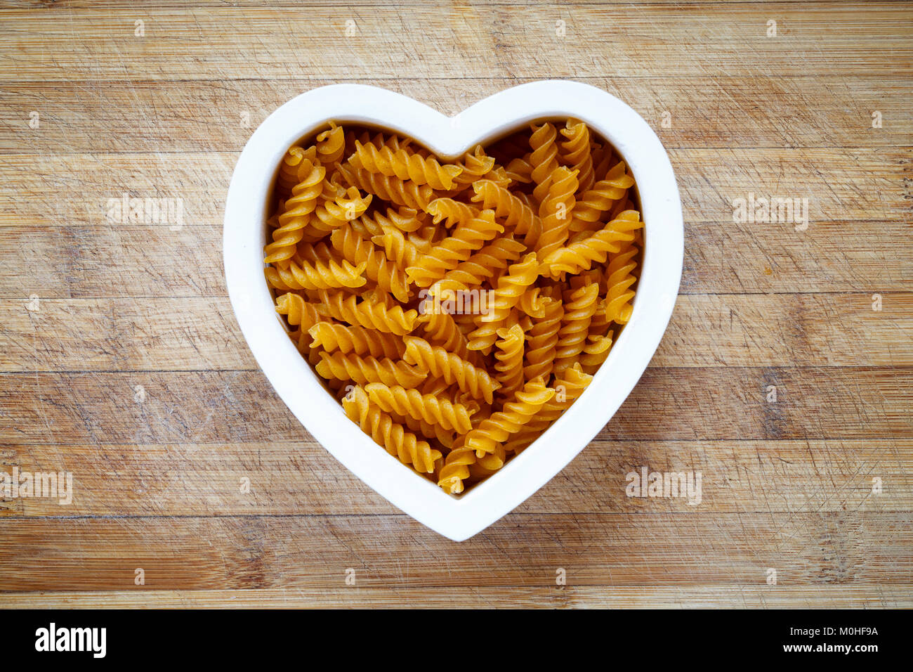 Herzförmige Schale mit glutenfreien Teigwaren gefüllt Stockfoto