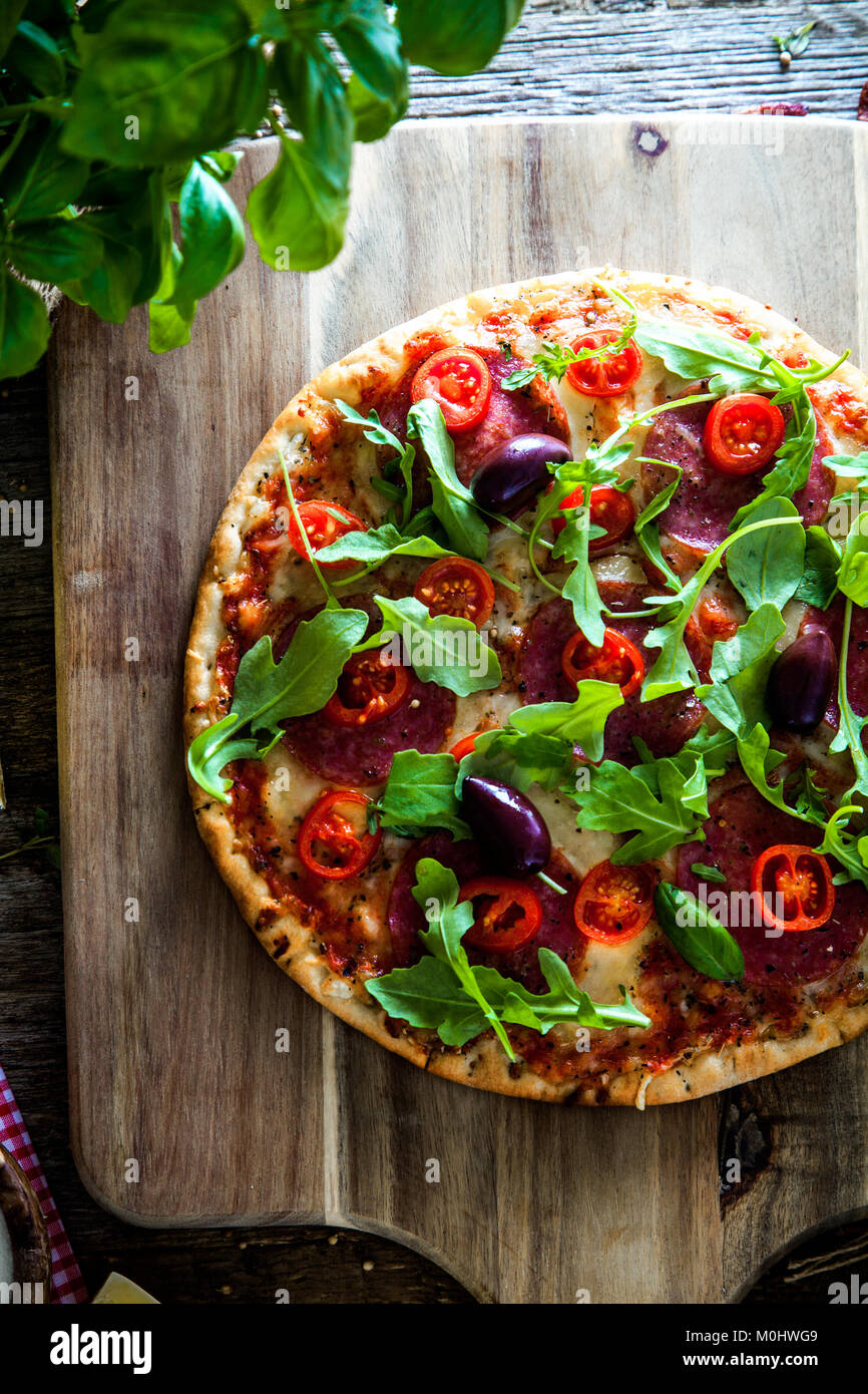 Frische italienische Pizza auf Holz. Pizza mit Käse, Salami und Tomaten. Fast food. Rustikale pizza Stockfoto