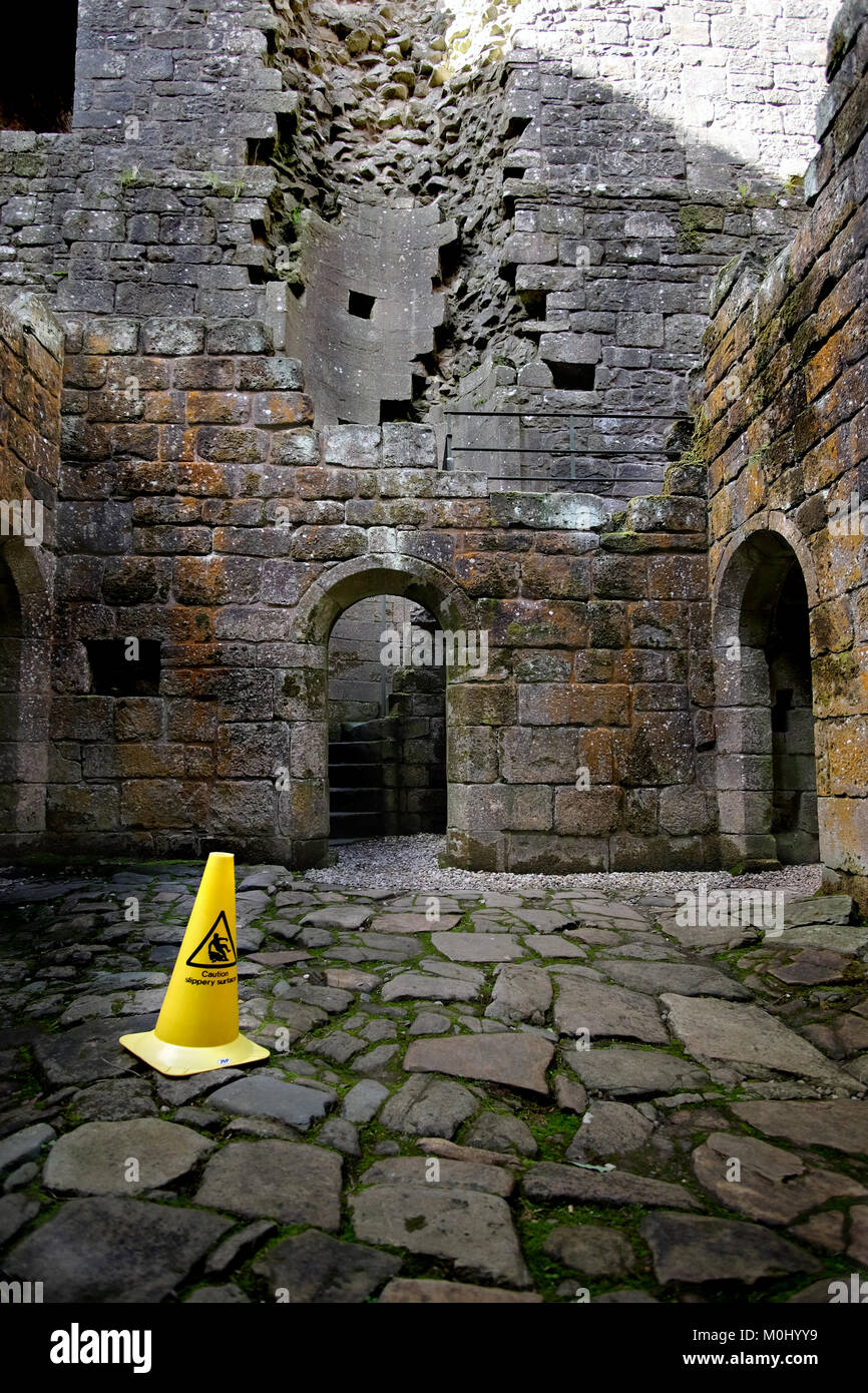 Ein Vorsichtshinweis rutschige Oberfläche Gefahr Poller auf dem nassen unebenem Boden im Hermitage Castle Stockfoto