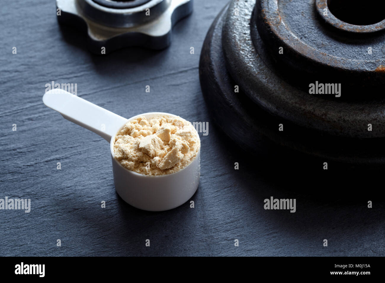 Messung der Schaufel mit Protein Pulver und Hantelscheiben auf dunklem Hintergrund gefüllt Stockfoto
