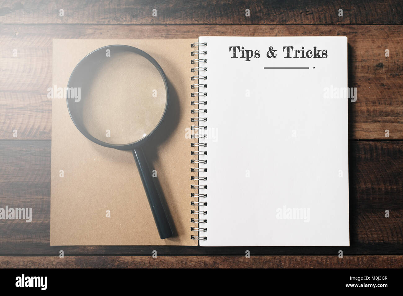 Lupe und Notebook mit TIPPS UND TRICKS word mit Kopie Speicherplatz auf Holztisch. Tipps und Tricks Konzept Stockfoto