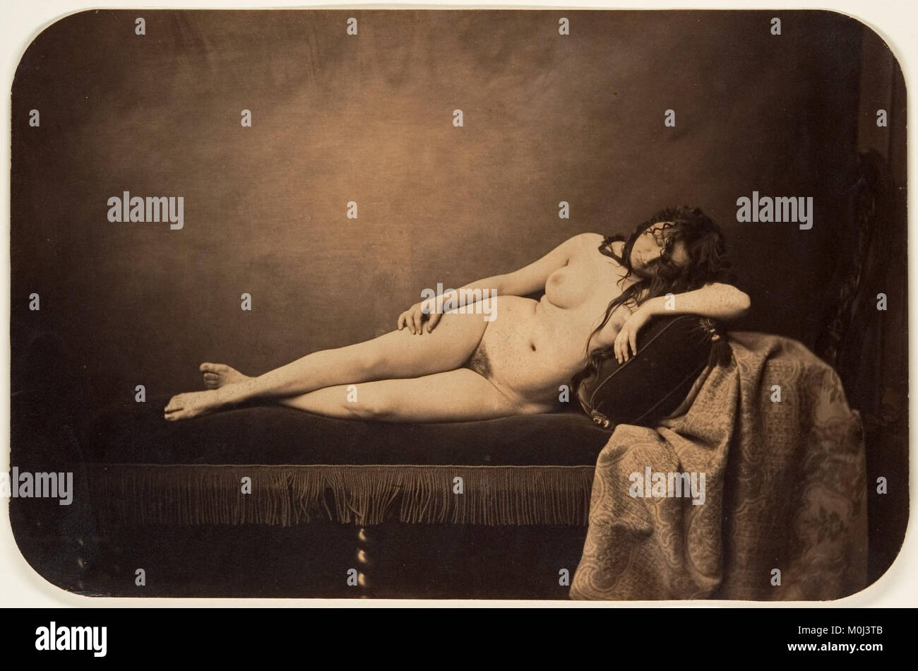 Dieses Gemälde zeigt eine liegende Frau, die in ruhiger Haltung auf einem Sofa ruht, in einem klassischen künstlerischen Stil, der anatomische Form, Vorhänge und kompositorische Balance betont. Stockfoto