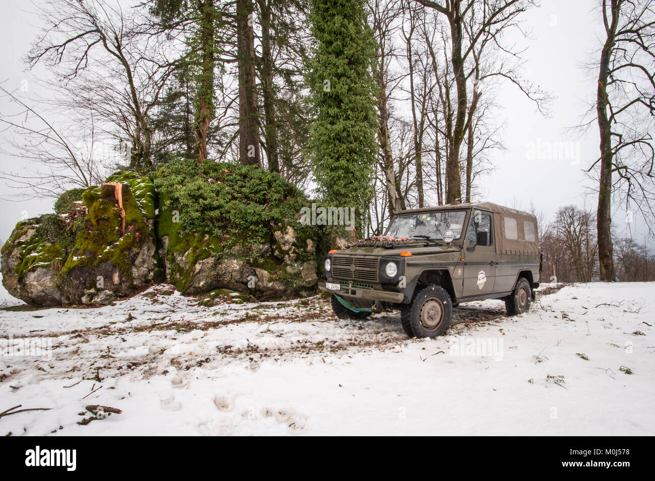 4x4 Puch Armee Fahrzeug parken vor einem Wald und Felsen in einer kalten, schneereichen Winter Tag Stockfoto