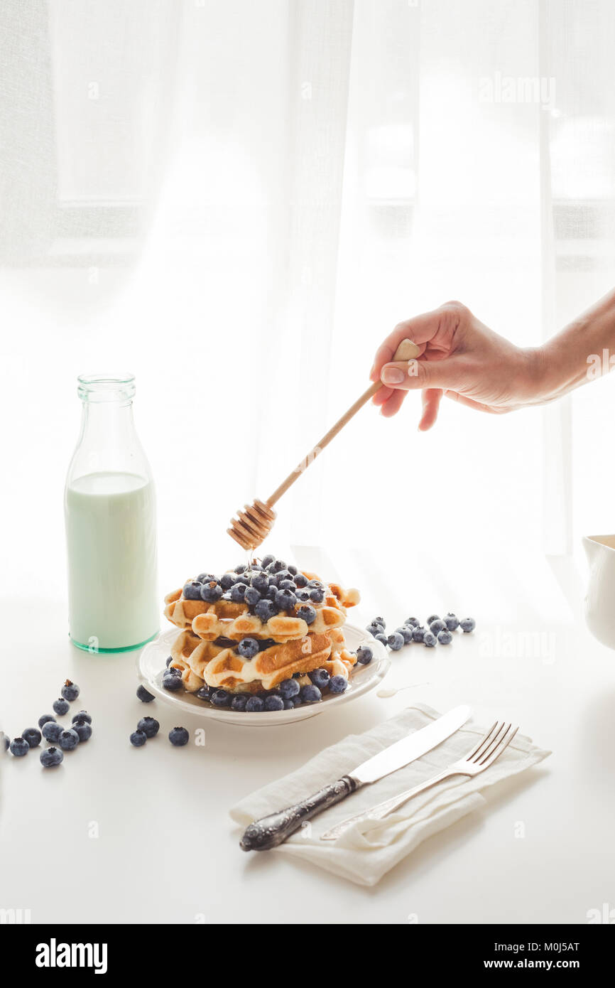 7/8 Schuß von Frau gießen Honig auf köstliche Waffeln Stockfoto