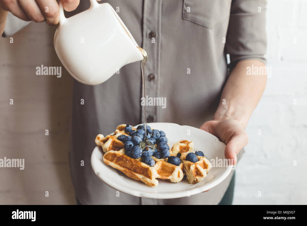 7/8 Schuß von Frau gießen Ahornsirup auf leckere Waffeln ...