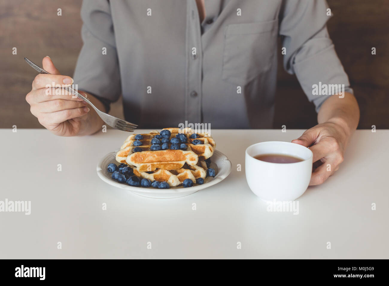 7/8 Schuß von Frau essen Waffeln mit Blaubeeren für Frühstück Stockfoto