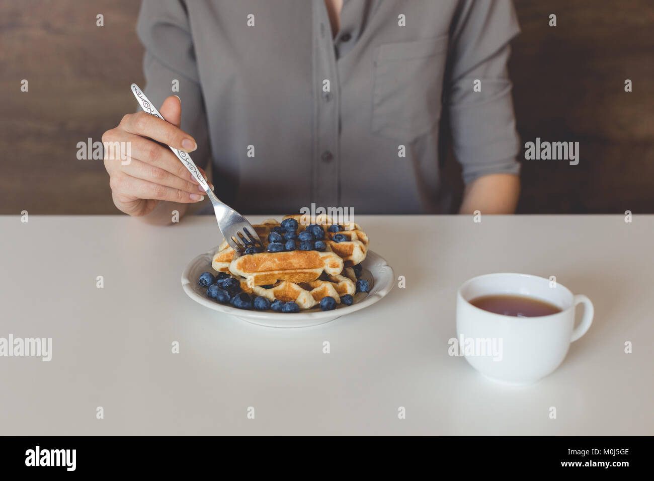 7/8 Schuß von Frau essen Waffeln mit Blaubeeren für Frühstück Stockfoto