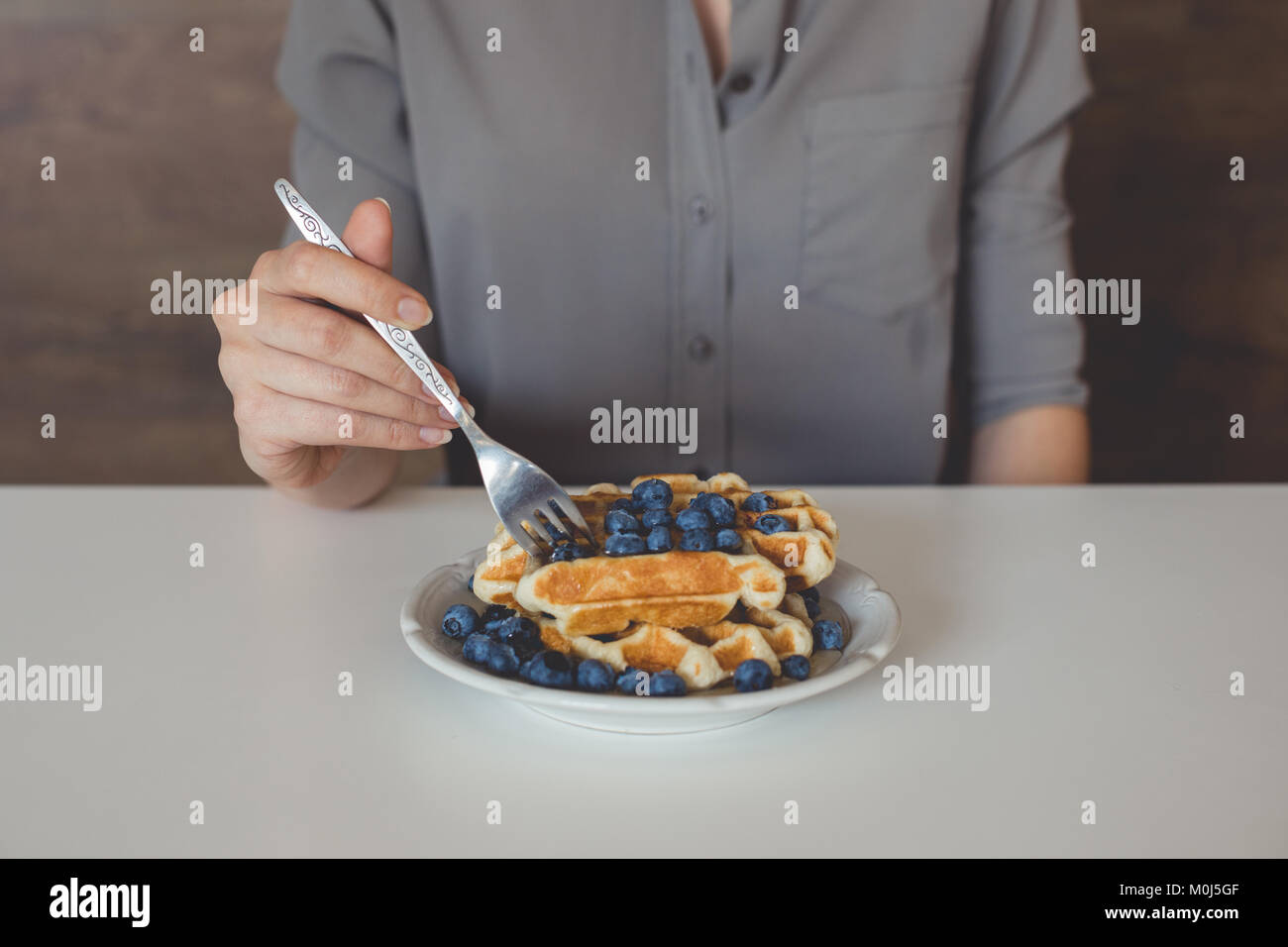 7/8 Schuß von Frau essen Waffeln mit Blaubeeren für Frühstück Stockfoto