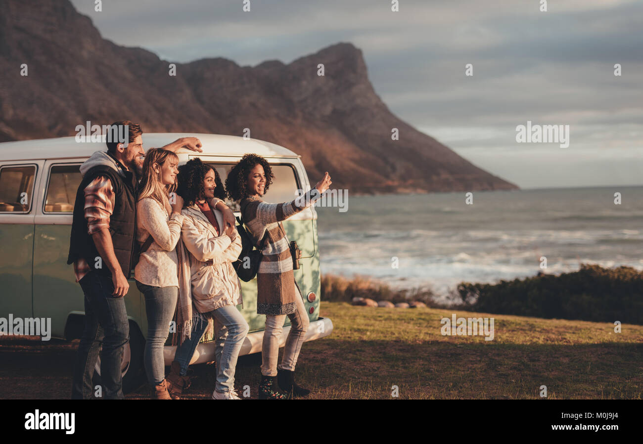 Freunde auf der Straße nach Selbstportrait mit Handy minivan. Gruppe von Mann und Frauen zusammen einen selfie während in der Nähe der va stehend Stockfoto