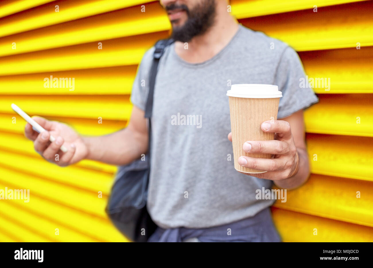 Mann mit Kaffeetasse und Smartphone über Wand Stockfoto