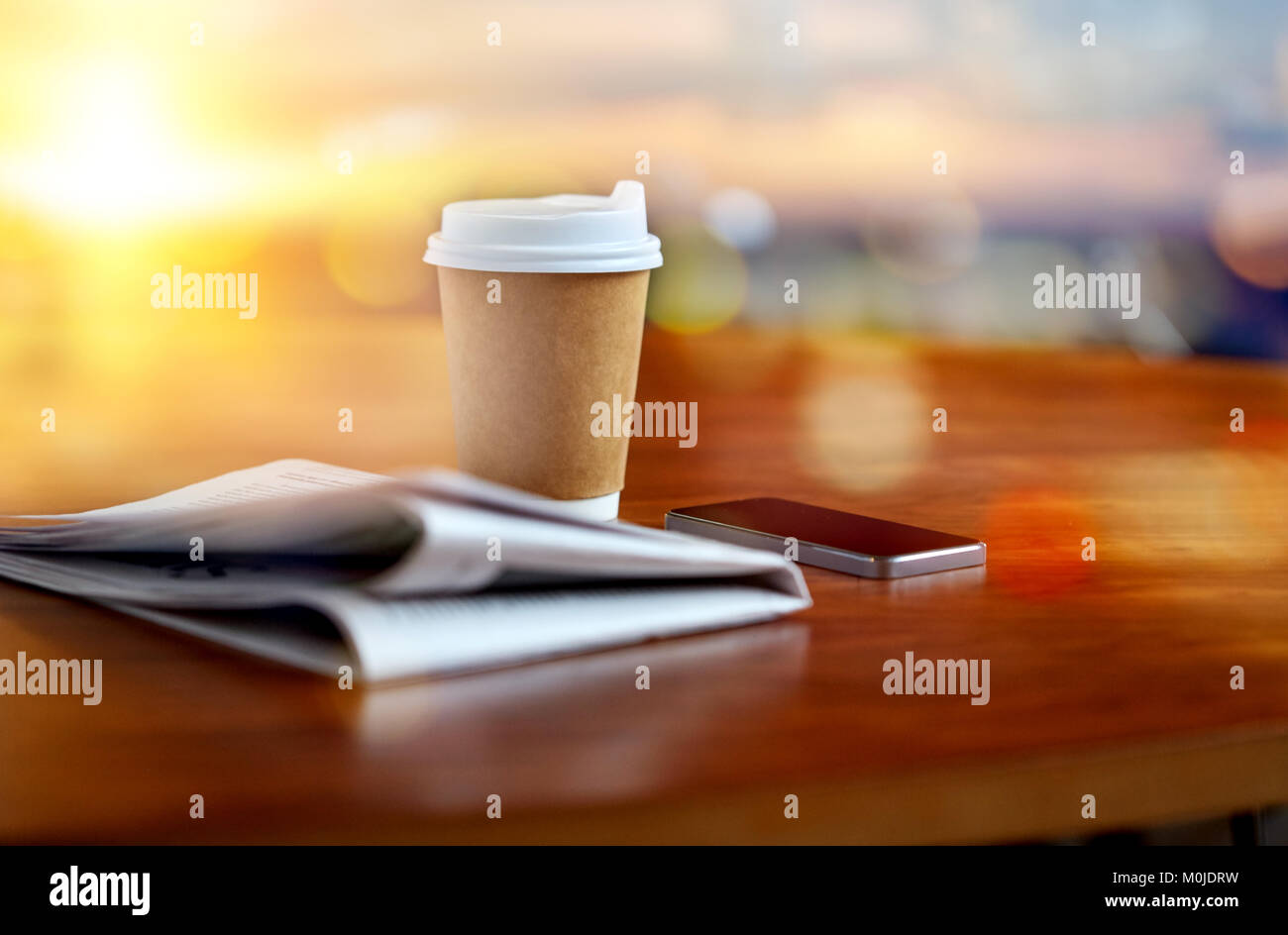 Kaffeetasse, Smartphone und Zeitung auf Tisch Stockfoto