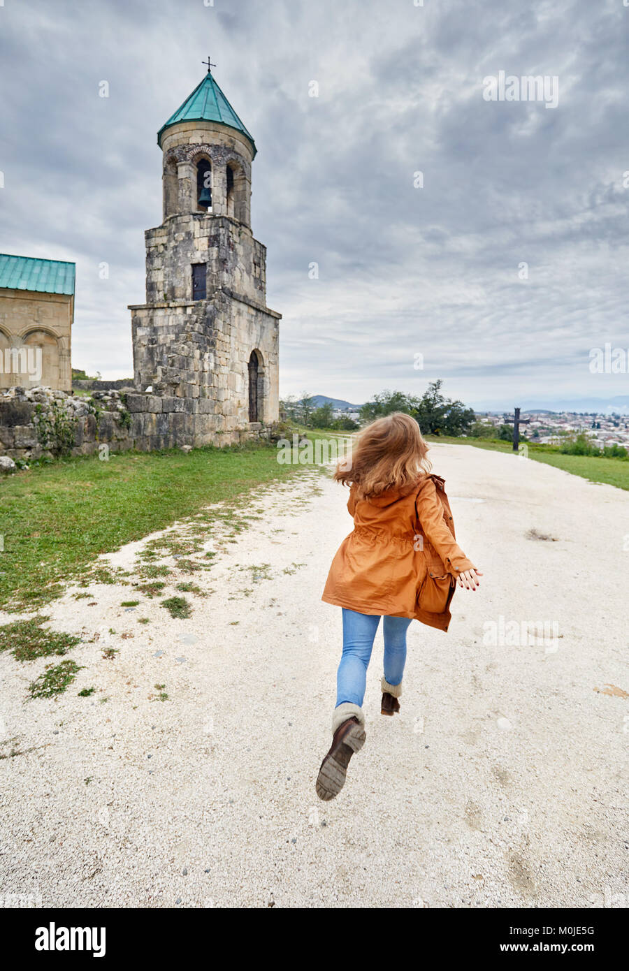 Frau zu laufen, um die Kapelle Turm von bagrati Kirche bei bedecktem Himmel in Kutaissi, Georgien Stockfoto