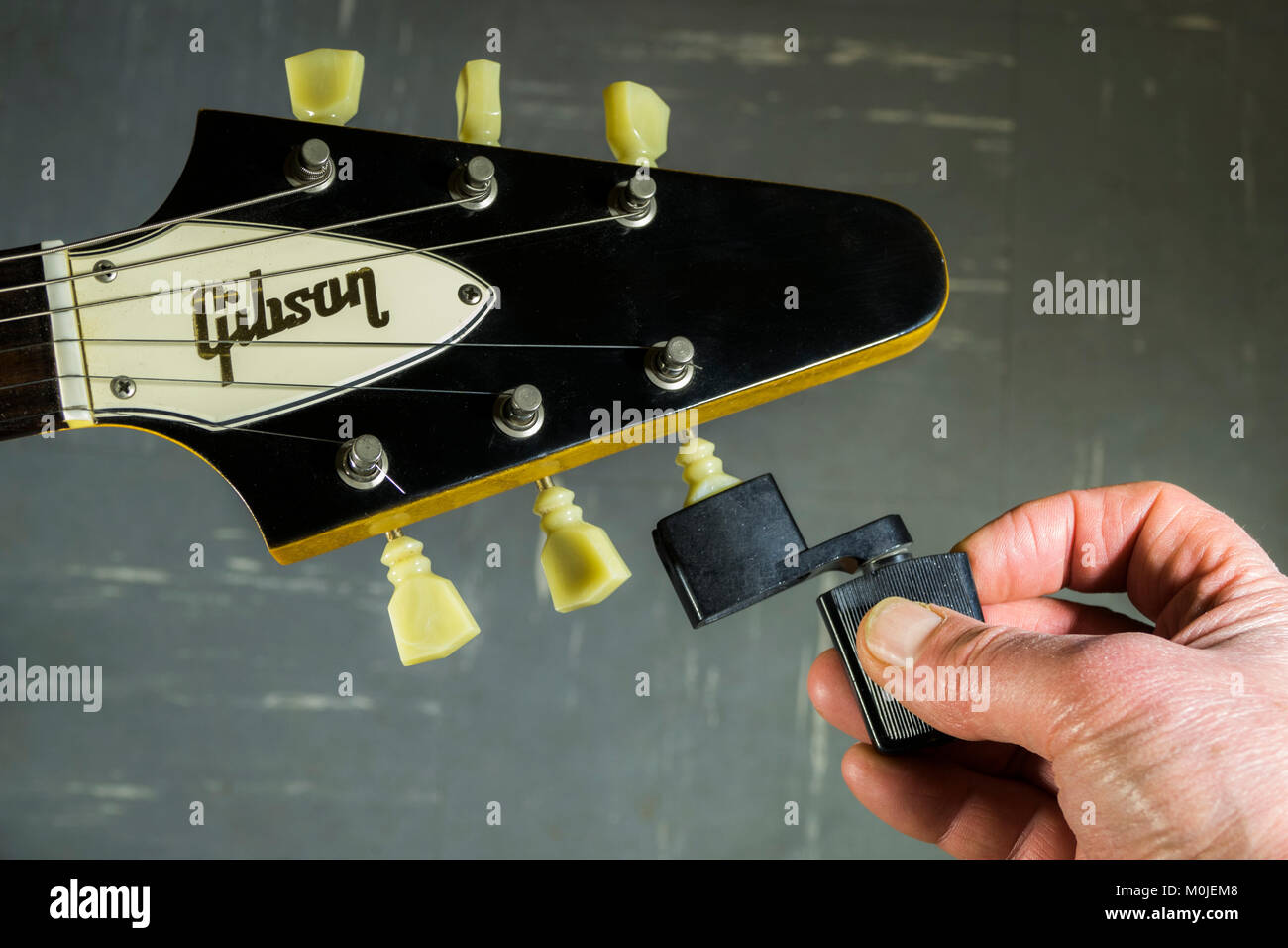 Gibson Flying V E-Gitarre Spindelstock, mit den Fingern ein Mann hält eine Saitenkurbel gegen ein Tuning peg/Tuner, einen String zu lösen oder festziehen. Stockfoto