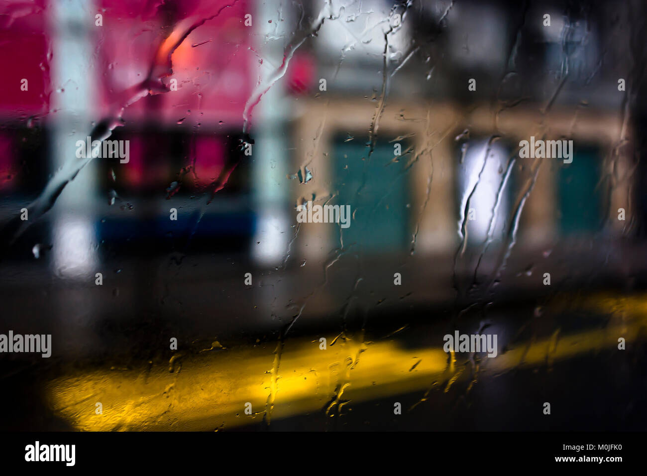 Blurry abstrakte regnerischen Tag, leere Straße der Stadt durch Bus-Fenster Glas mit Regentropfen Stockfoto