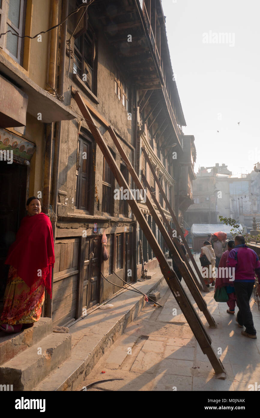 Frauen steht am Eingang des Gebäudes propped up mit Holz unterstützt, nach Erdbeben Schäden, Kathmandu, Nepal Stockfoto