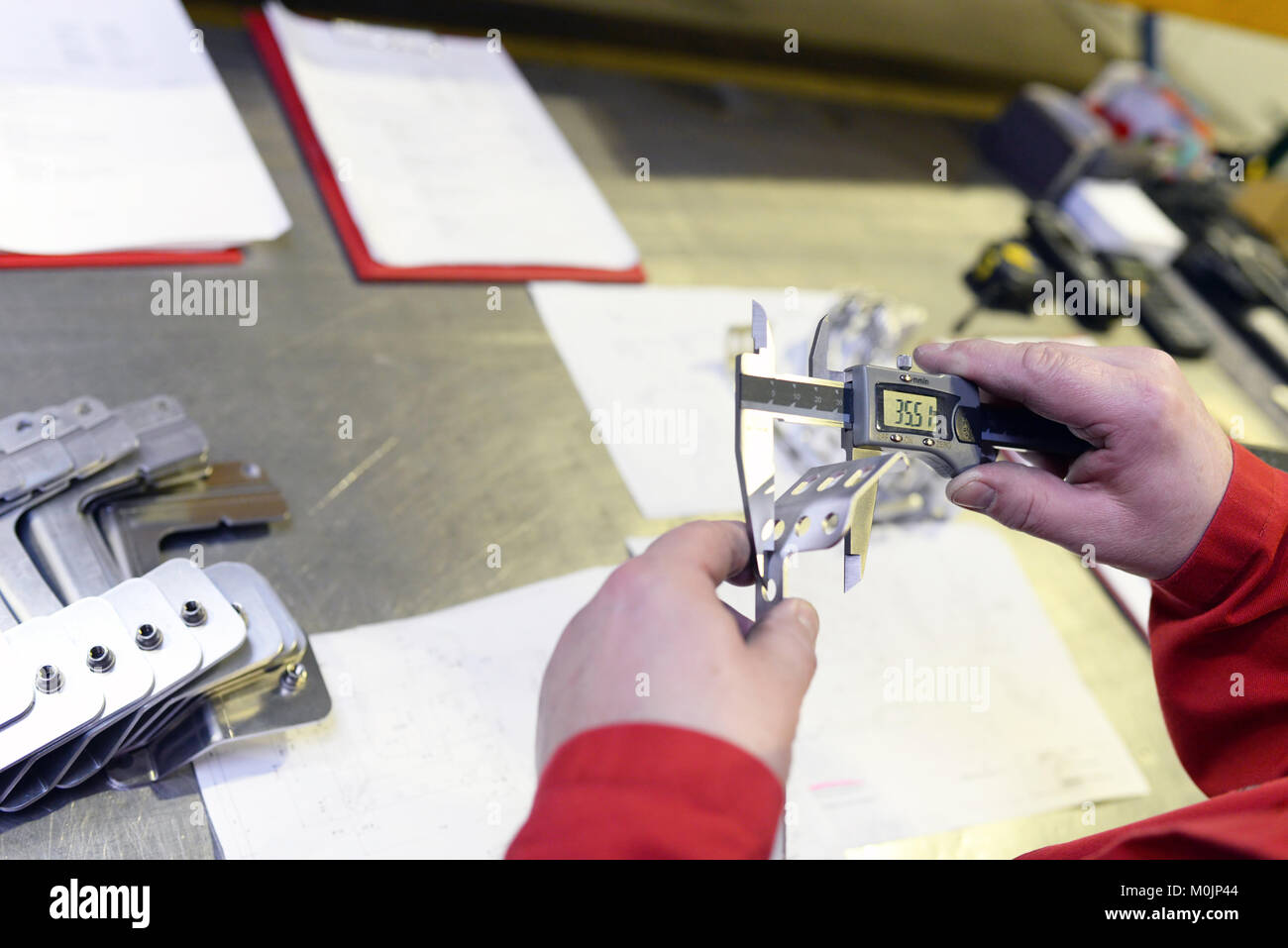 Gewerbliche Arbeitnehmer prüfen arbeiten Stück für Genauigkeit mit Messgerät Stockfoto