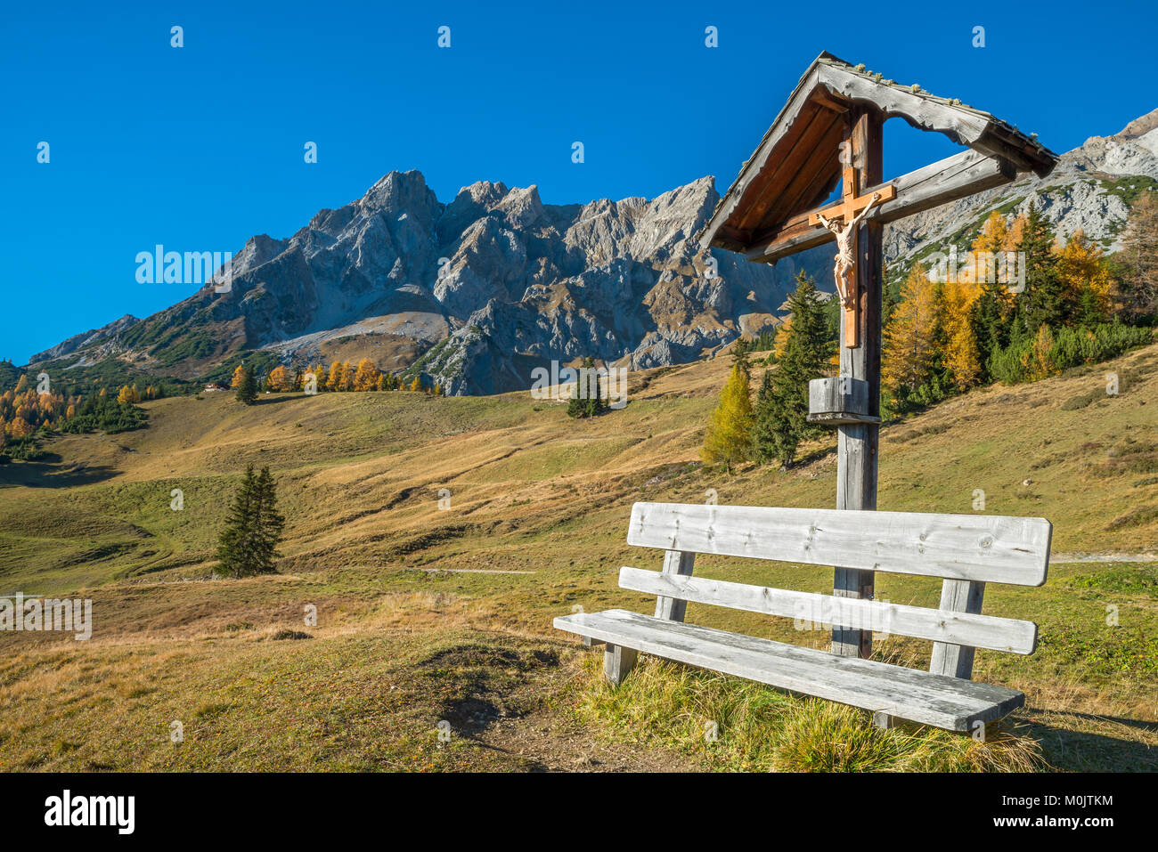 Kreuz aus Holz und Sitzbank, dahinter das Eisenspitze, Dawin-Alpe, Strengen am Arlberg, Tirol, Österreich Stockfoto