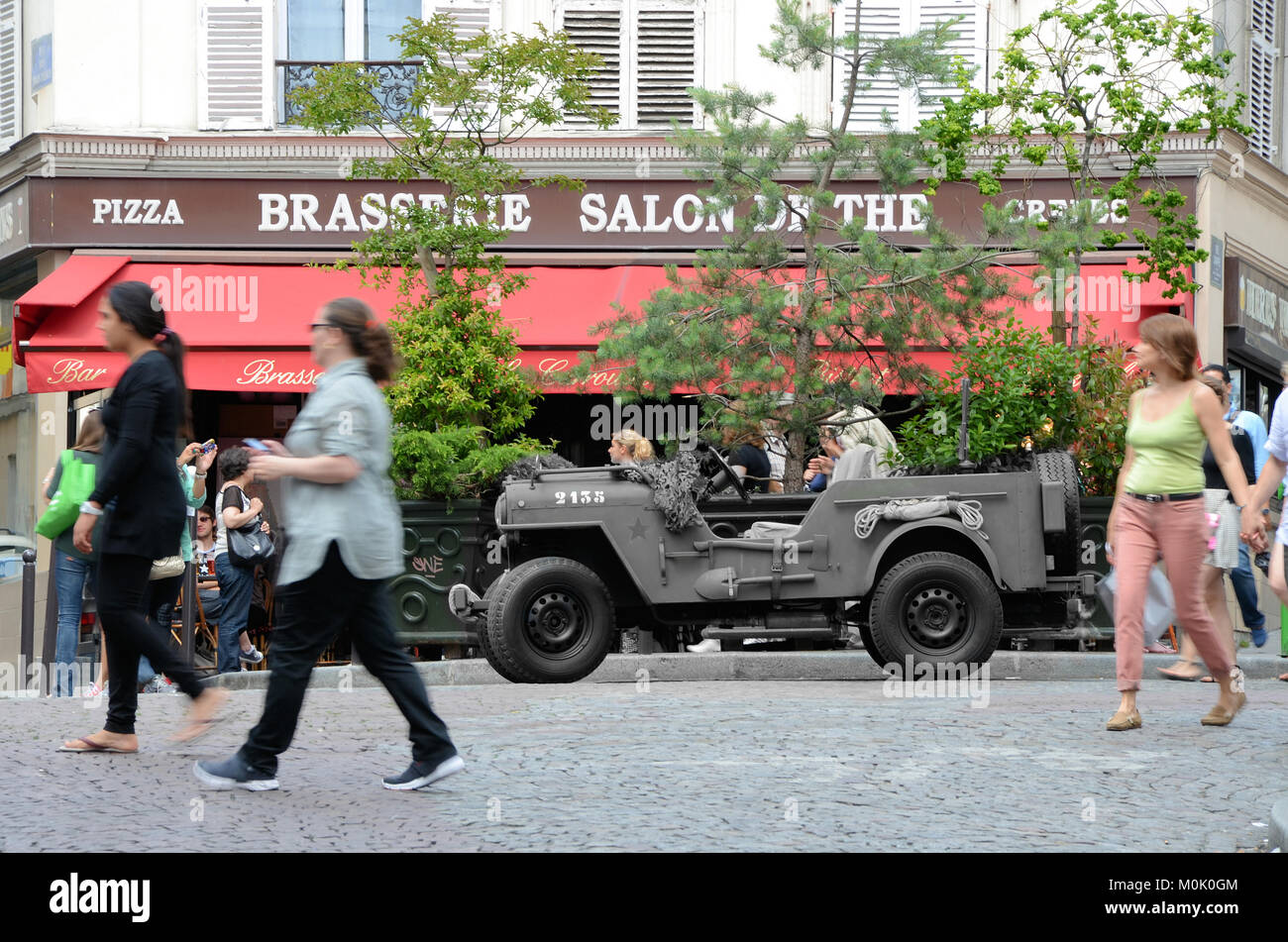 Kriegszeit US Jeep in Paris, vor der Brasserie Salons de thé im Pariser Viertel Montmartre, Frankreich mit Jeep in monochromer Form. Time Warp-Konzept Stockfoto