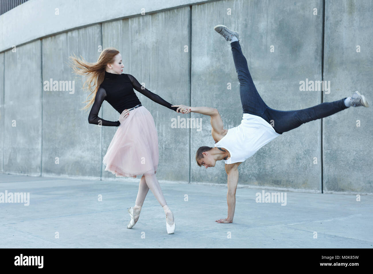 Ein junges Paar in der Liebe leidenschaftlich tanzt auf einer Straße der Stadt. Tänzerin und Sportler Parkour. Balance und Stunts im Tanz. Meshenie klassische und mod. Stockfoto