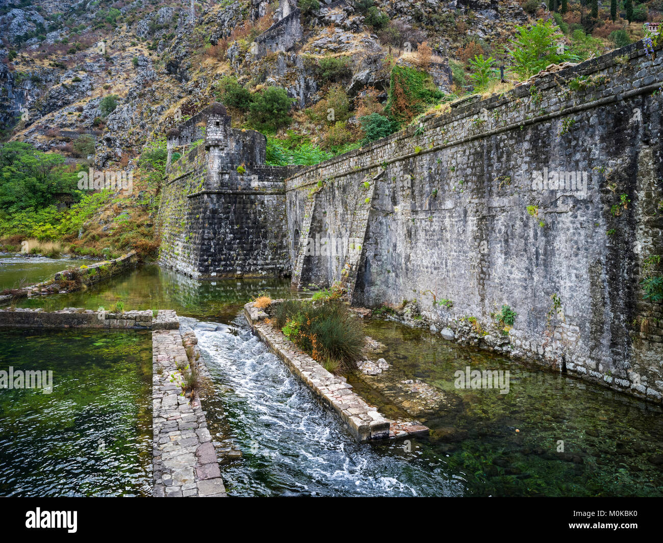 Eine verschlissene Steinwand mit Wasserfällen entlang der Bucht von Kotor und Kotor, Montenegro Stockfoto