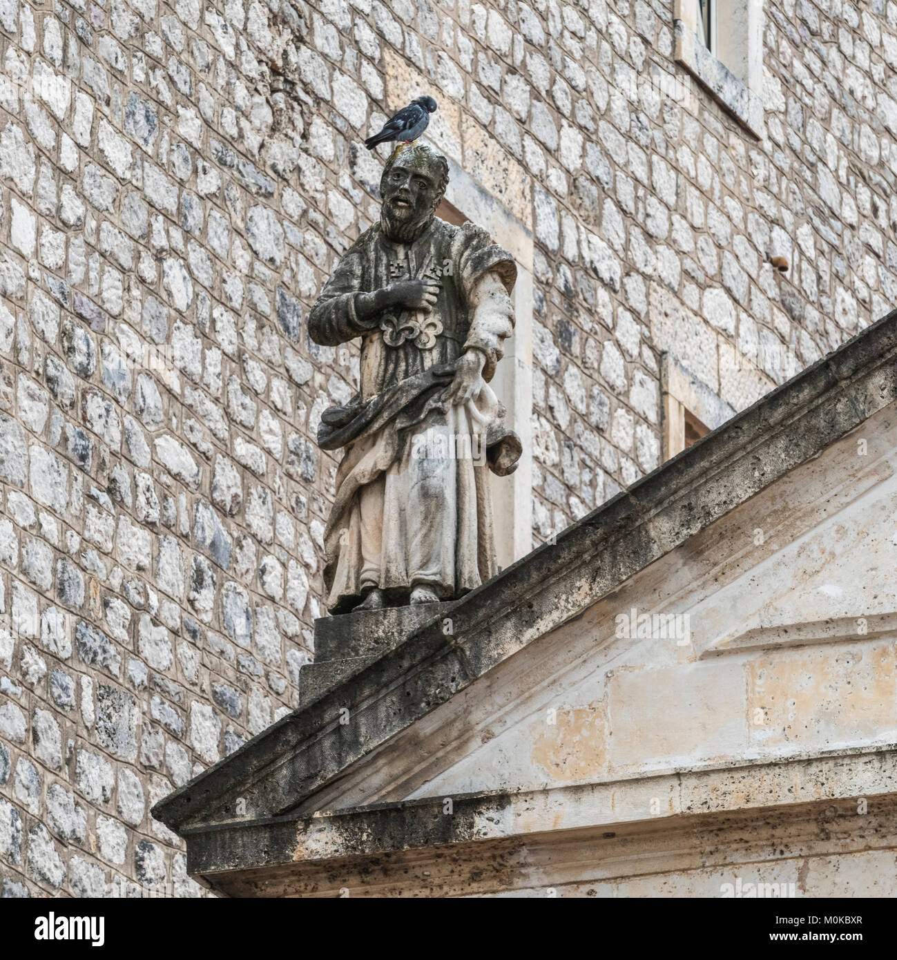 Ein Vogel auf den Kopf einer Statue neben einer Mauer eines Gebäudes; Perast, Kotor, Montenegro Stockfoto Ein Vogel auf den Kopf einer Statue neben einer Mauer eines Gebäudes; Perast, Kotor, Montenegro Stockfoto