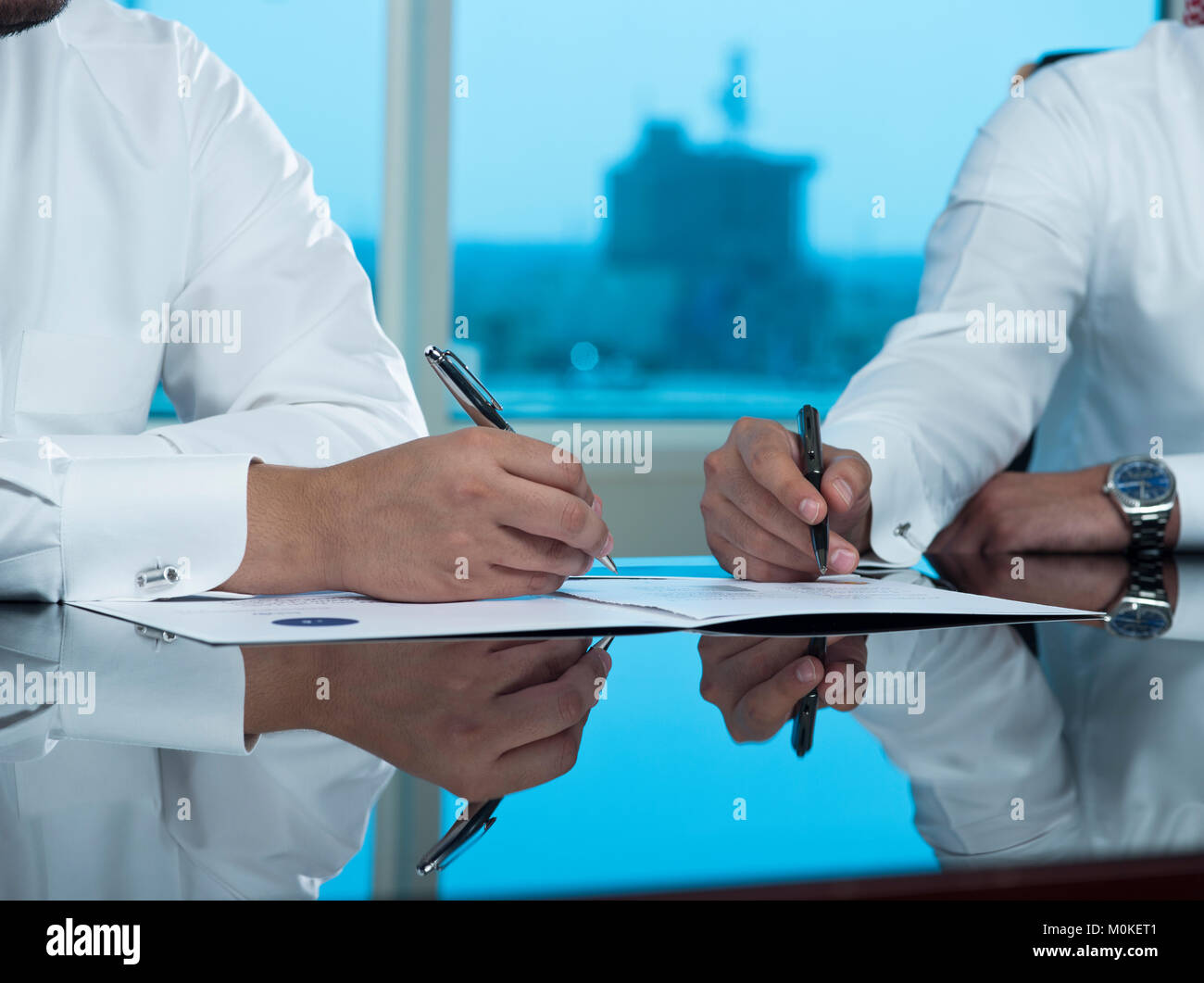 Zwei saudische Geschäftsleute Hände Signieren eines Dokuments, Vertrag oder einen Deal Stockfoto
